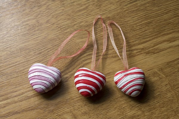 3 pendants in heart shape on wooden plate for decoration