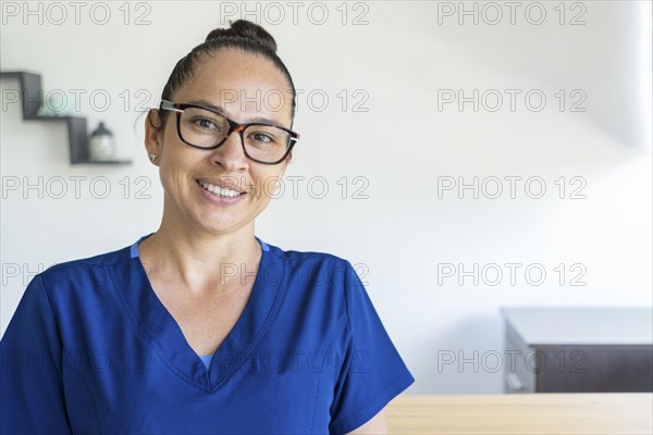 Woman in glasses wears a blue uniform looks at the camera smiling. Close up and copy space. Medical concept