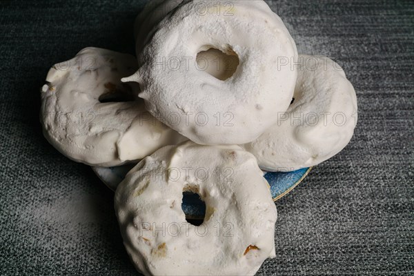 Sugar glazed donuts on a blue plate covered with icing sugar on a black background and copy space