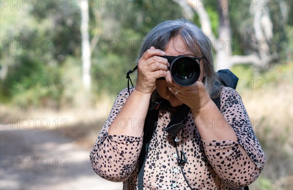 White-haired female photographer seen from the front taking pictures with her camera