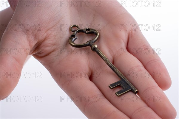 Hand holding a retro styled metal key on a white background