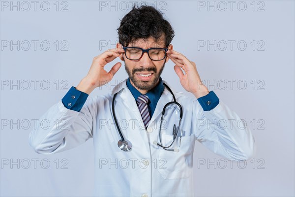 Young Doctor suffering with headache isolated. Doctor with migraine holding his head