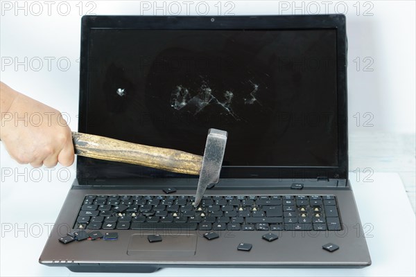 Arm of a man breaking a laptop with a hammer isolated on white background and copy space