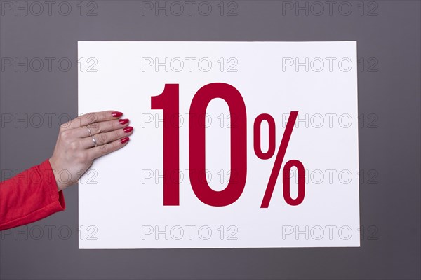 Female hand holding a 10% poster. Studio shot. Commercial concept