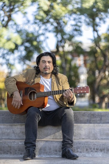 Flamenco guitarist sitting on some stairs performing