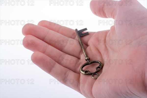 Hand holding a retro styled metal key on a white background