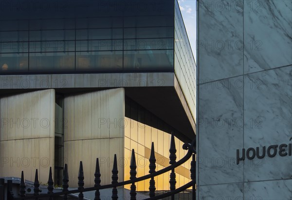 Facade of Acropolis museum facing Acropolis reserch center mirroring the sunset