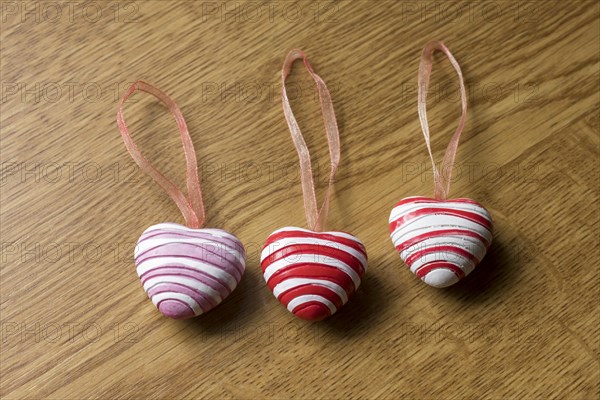 3 pendants in heart shape on wooden plate for decoration