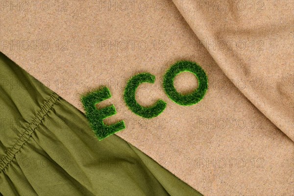 Concept for environmental friendly produced clothing with text 'ECO' made out of grass on textiles