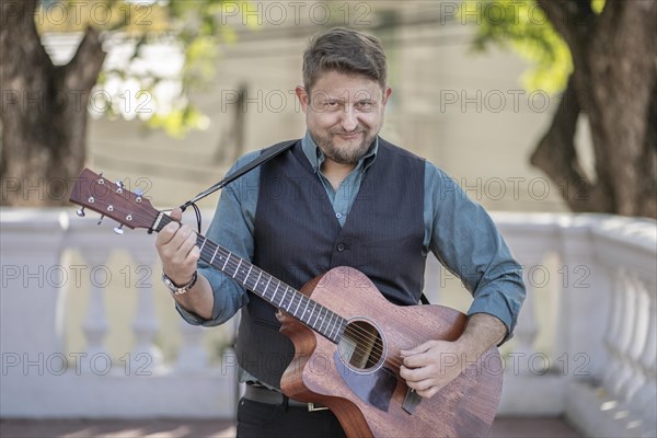 Guitarist performing in a park looking at the camera