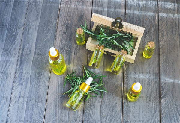 Top view of dropper bottles with rosemary essential oil in a wooden box on a wooden table