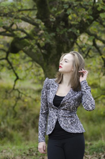 Beautiful young woman standing in the countryside looking away