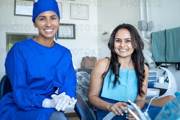 Smiling young woman in dental exam with her dentist both look at camera