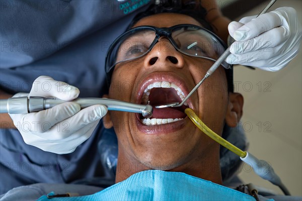 Male patient visits dental office. Dentist wearing rubber protective gloves performs dental treatment