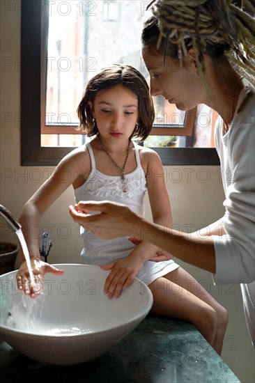 A cute little girl and her mother are washing their hands. Protection against infections and viruses