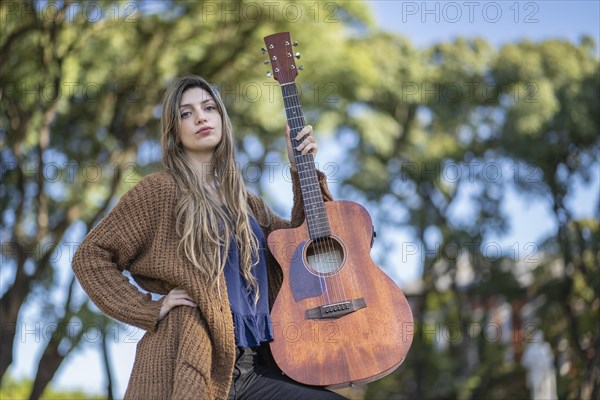 Young blonde woman with her guitar in the park. Concept of creative hobbiess and professionals. Positive attitude. Empowerment