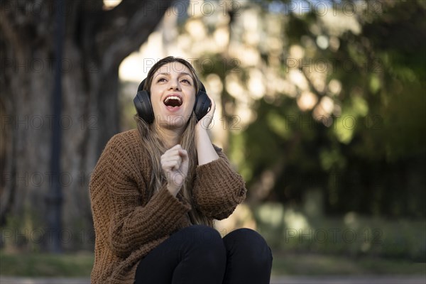 Blonde woman sitting on the street listening to music