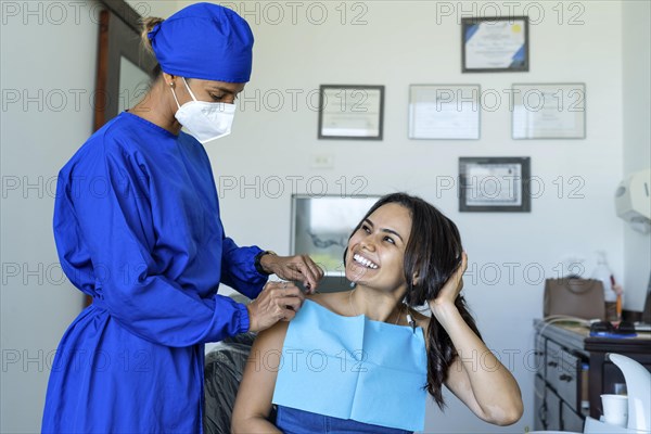 Female patient smiles and looks at her dentist in the dental office. Background with professional titles out of focus