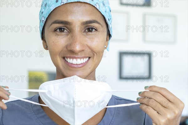 Beautiful doctor smiles at the camera while removing her mask