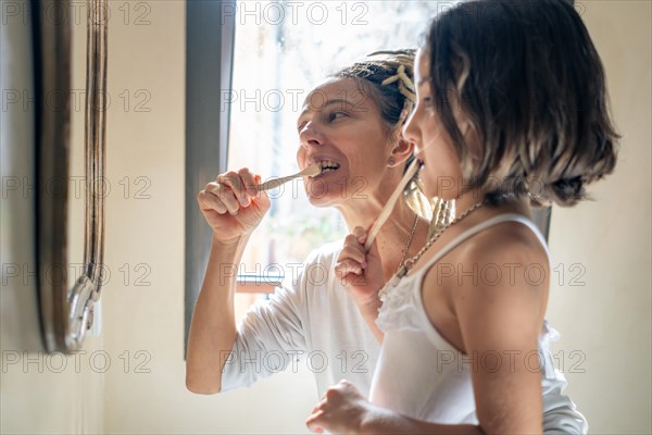 Mother teaching little girl how to brush her teeth. Mother and daughter at home