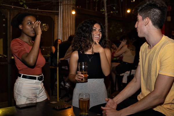 Friendly three Mixed-race drinking beer in a bar. Multiethnic concept