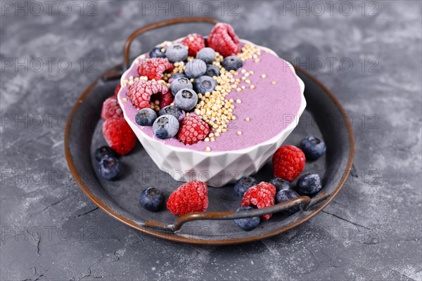 Fruit smoothie bowl with pink yogurt decorated with healthy raspberry