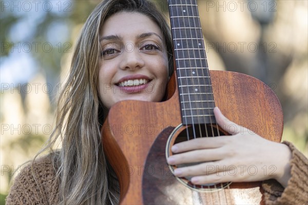 Young blonde woman with her guitar in the park. Concept of creative hobbiess and professionals. Positive attitude. Empowerment