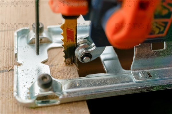 Close-up of an electric saw cutting wood chips jumping out of the wood with the blade in motion