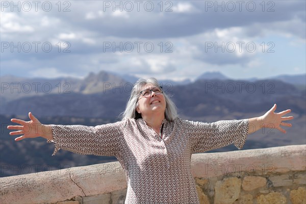 Old white-haired woman with her arms outstretched