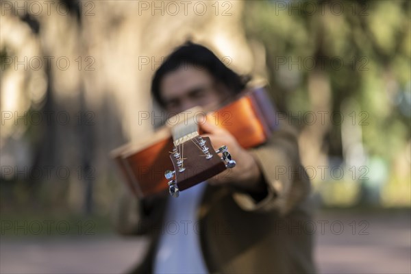 Hispanic man pointing his guitar to the camera. Inspirational concept