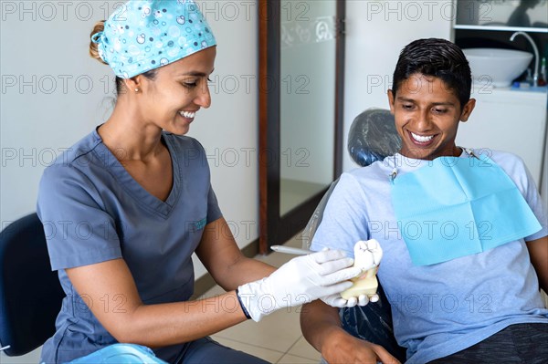Dentist showing a patient a model of a molar to explain the treatment