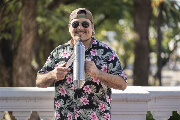 Hispanic artist playing gueiro in the street