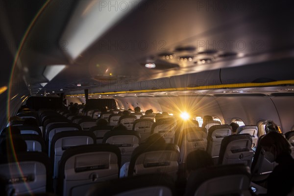 The sun shines into a window of a plane with travellers to Frankfurt