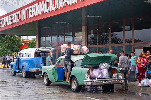 Cubans loading their old American cars with loads of imported foreign merchandise in front of the Antonio Maceo Airport in the city Santiago de Cuba