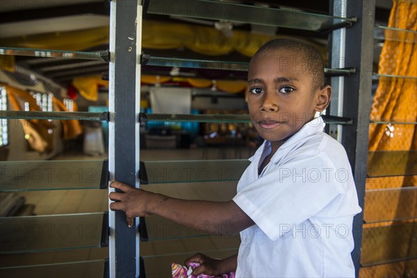 School boy cleaning the windows of their school