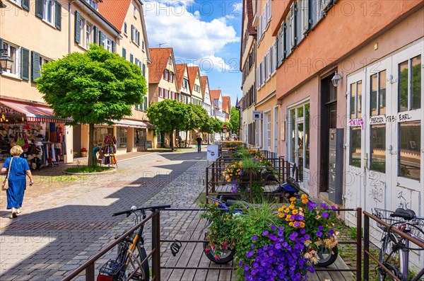 Street scene in Ammergasse with passers-by and shops as well as colourful flower decorations