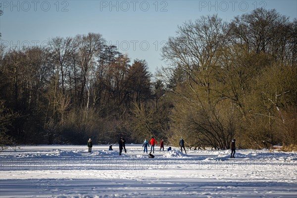 People walk across the ice and skate on the frozen Hermsdorfer See lake in Berlin Reinickendorf. Berlin