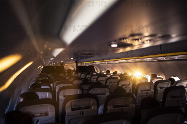 The sun shines into a window of a plane with travellers to Frankfurt