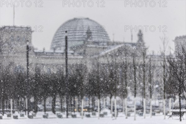 The Reichstag building is silhouetted against snowfall in the government district in Berlin