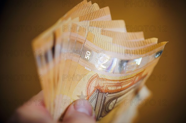 Symbolic photo on the subject of cash. 50 euro banknotes are held in one hand. Berlin