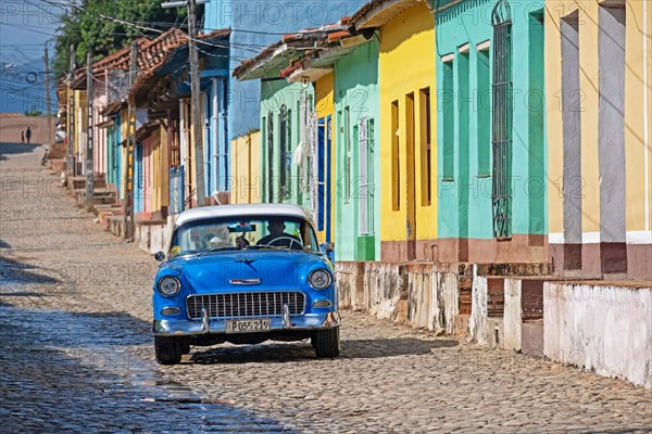 Blue vintage American Chevrolet car in colonial cobbled street with pastel coloured houses in the city Trinidad