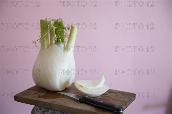 Fresh fennel bulb with knife on a wooden board