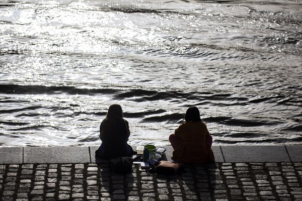 Two woman relaxing in the midday sun at the Spreebogen in the government district in Berlin