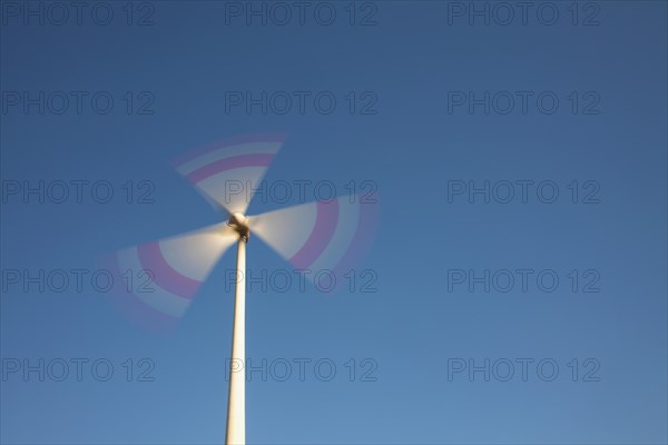 Spinning blades of windturbine against blue sky