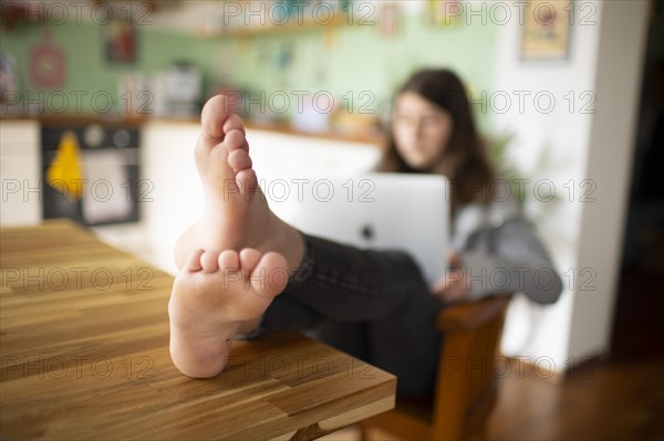 Subject: Girl sitting with feet on the table in the living room using a mobile phone