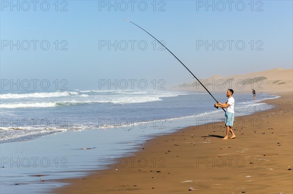 Fisherman standing by Atlantic Ocean