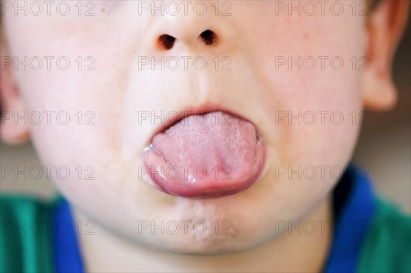 Symbolic photo on the subject of the defiant phase. A five-year-old boy sticks out his tongue. Berlin