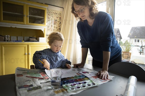 Subject: Mother occupies her child with watercolours