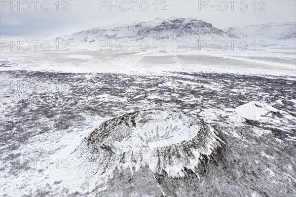 Aerial view over the Eldborg volcanic crater in the Eldborgarhaun lava field covered in snow in winter