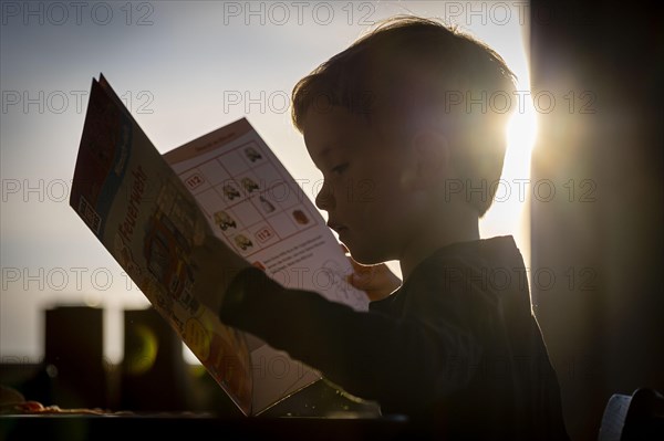 Symbolic photo: A little boy looks at a picture book. Berlin